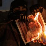 A protester burns an image of Ali Khamenei during a protest outside the Iranian Embassy on January 14, 2026 in London, England