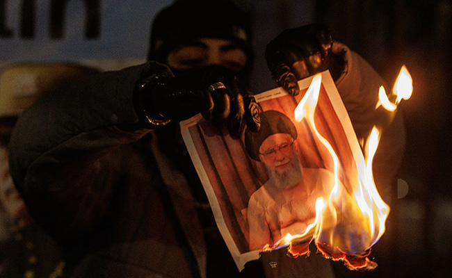 A protester burns an image of Ali Khamenei during a protest outside the Iranian Embassy on January 14, 2026 in London, England