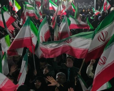 Pro-government supporters wave Iranian flags during a rally in a square in western Tehran, Iran, Wednesday, March 25, 2026. (AP Photo/Vahid Salemi)