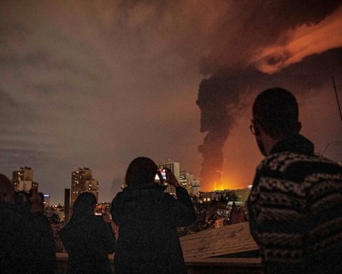 Residents look on and take pictures as flames and smoke rise from an oil storage facility struck as attacks hit the city during the US-Israeli military campaign in Tehran, Iran, Saturday, March 7, 2026. (Alireza Sotakbar/ISNA via AP)