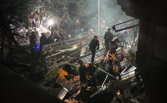 Israeli security forces and rescue teams work amid the rubble of a residential building struck by an Iranian missile in Haifa, Israel, Sunday, April 5, 2026. (AP Photo/Ariel Schalit)
