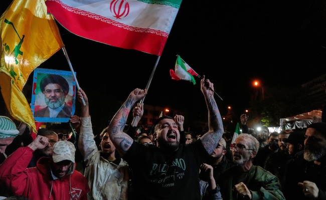 Pro-government demonstrators chant slogans as they hold Iranian flags and a poster of the Supreme Leader Ayatollah Mojtaba Khamenei in a gathering after announcement of a two-week ceasefire in the war with the United States and Israel, at the Enqelab-e-Eslami, or Islamic Revolution, Square, in Tehran, Iran, Wednesday, April 8, 2026. (AP Photo/Vahid Salemi)