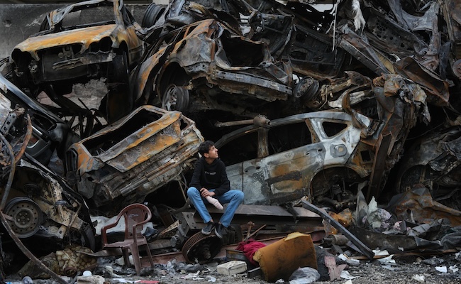 A man sits next to charred cars and wreckage where a building was destroyed by an Israeli airstrike the previous Wednesday, in central Beirut, Lebanon, Tuesday, April 14, 2026. (AP Photo/Hassan Ammar)