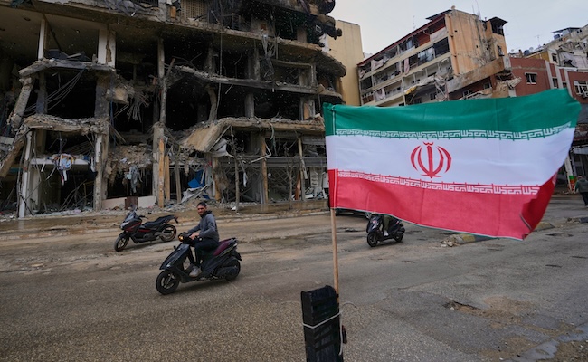 A man on his scooter passes next to an Iranian flag placed in front of a destroyed building, following a ceasefire between Hezbollah and Israel, in Dahiyeh, Beirut's southern suburbs, Lebanon, Monday, April 20, 2026. (AP Photo/Hussein Malla)
