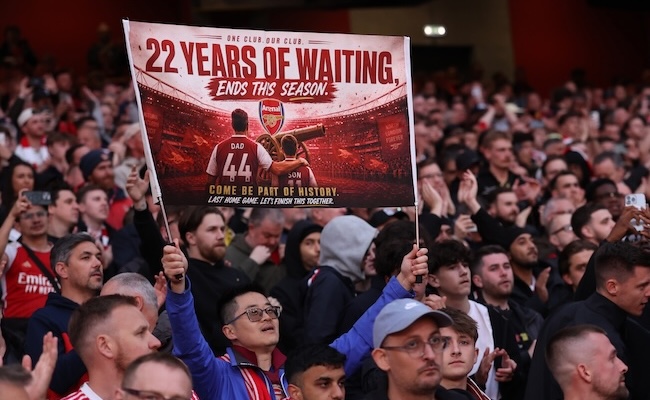 LONDON, ENGLAND - MAY 18: An Arsenal fan holds up a sign saying ' 22 years of waiting ends this season' in reference to Arsenal possibly winning the Premier League ahead of the Premier League match between Arsenal and Burnley at Emirates Stadium on May 18, 2026 in London, England. (Photo by Catherine Ivill - AMA/Getty Images)