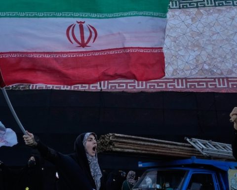 A woman waves an Iranian flags as she chants slogans against Iran and U.S. talks at the Islamic Revolution square in Tehran, Iran, Sunday, June 14, 2026. (AP Photo/Vahid Salemi)